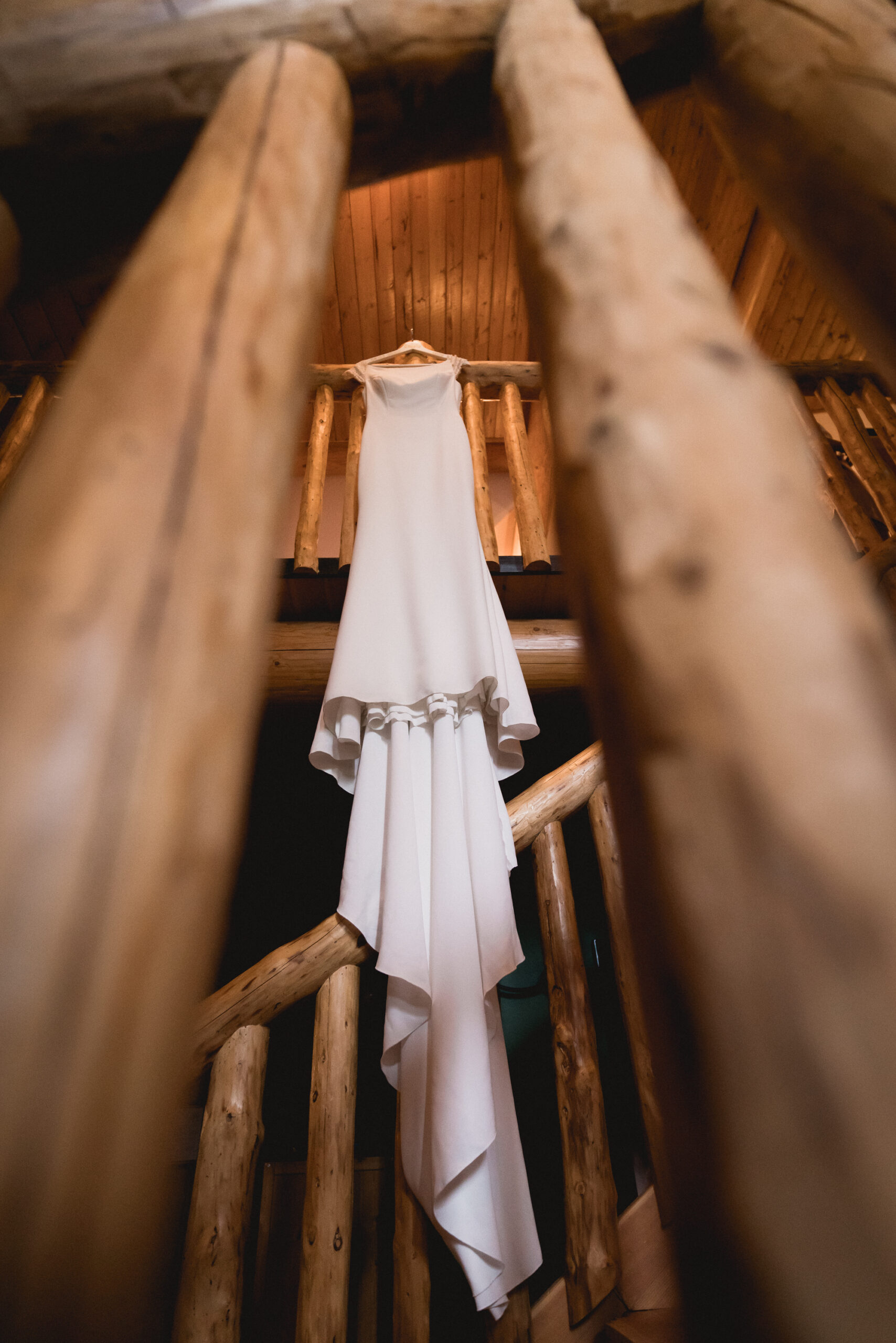 Classic wedding dress hanging down between two beams in a luxury log cabin