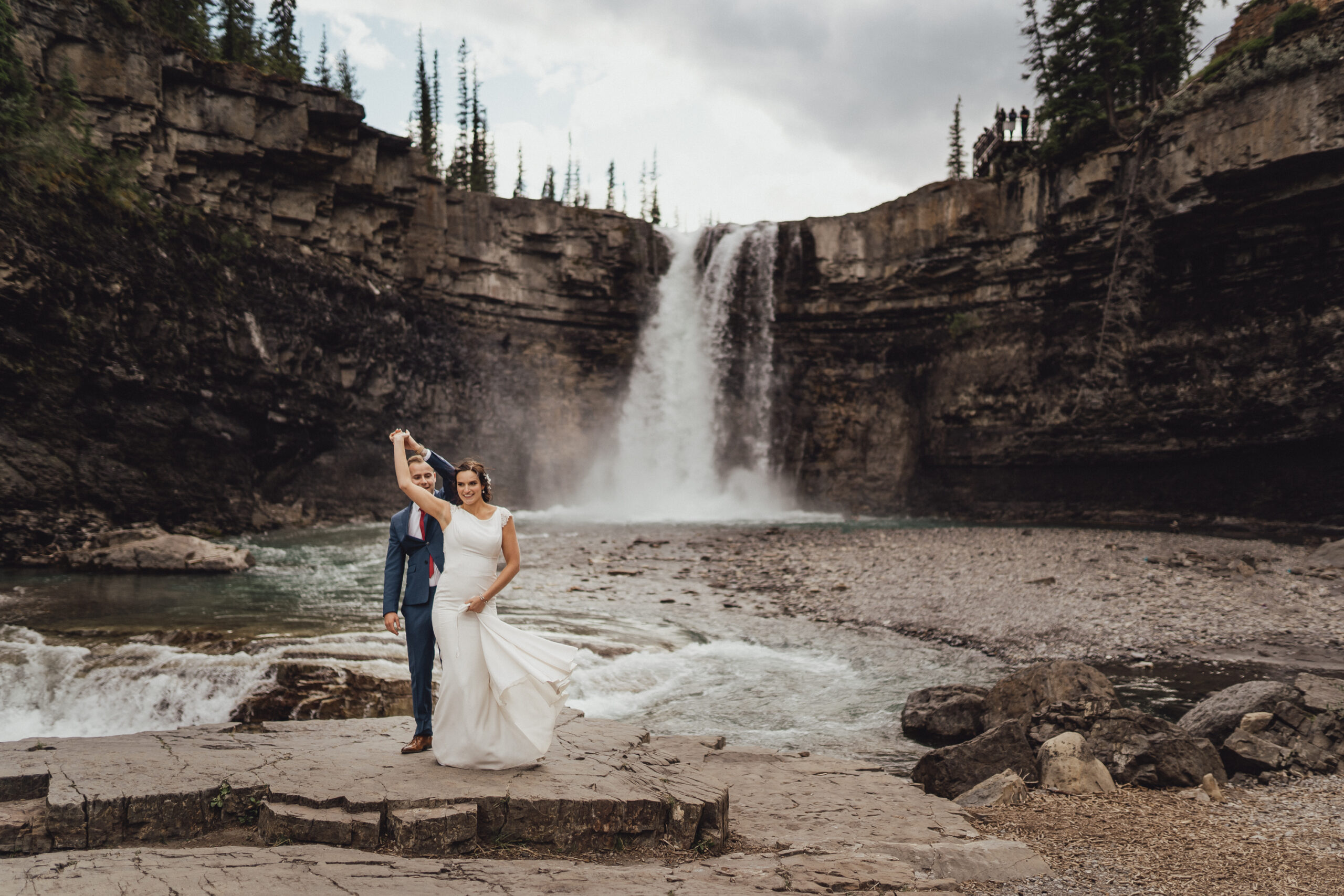 Classic wedding couple dancing in front of waterfall