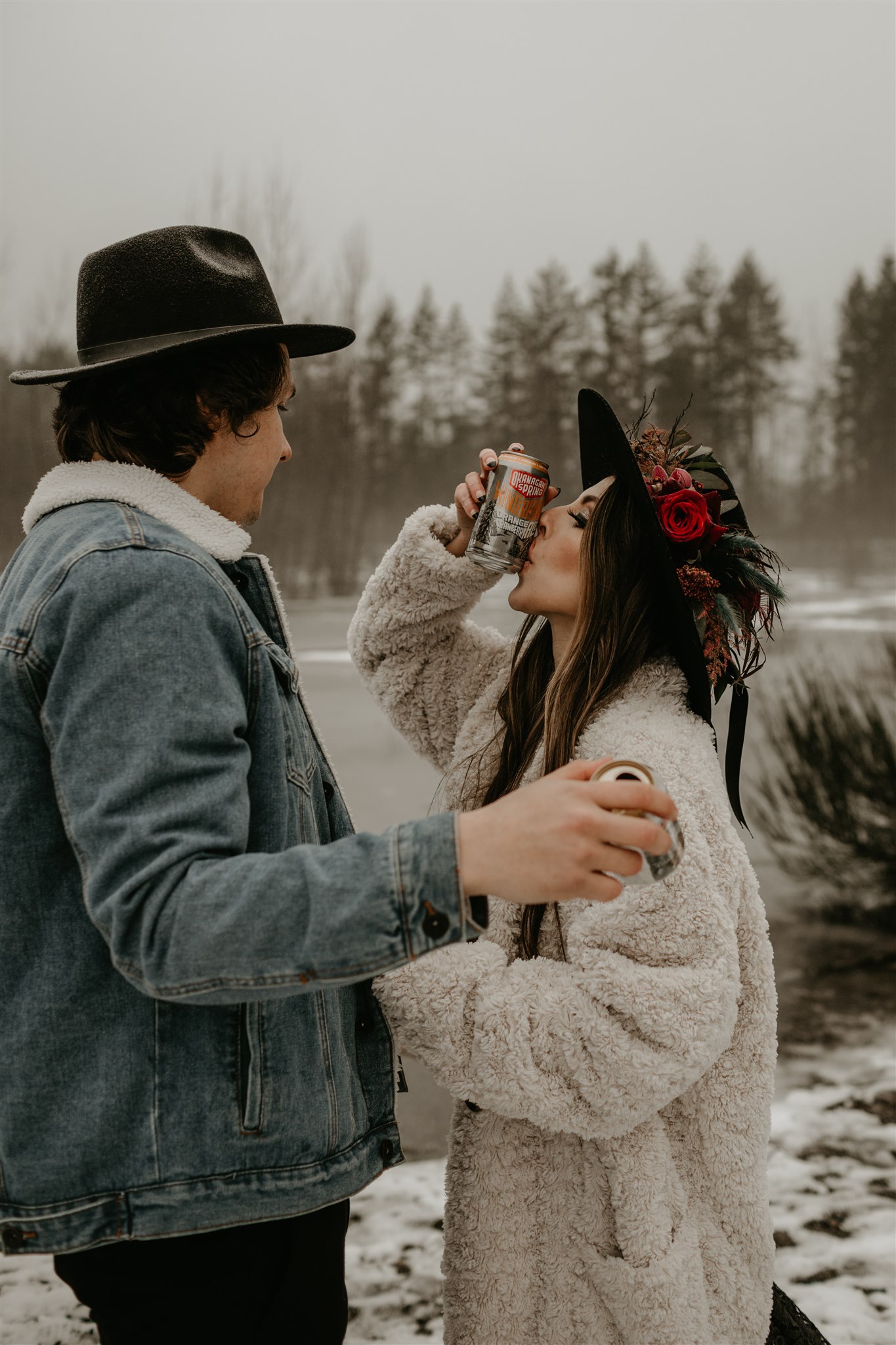 Boho chic bride in furry jacket and groom in jean jacket on snowy river bank