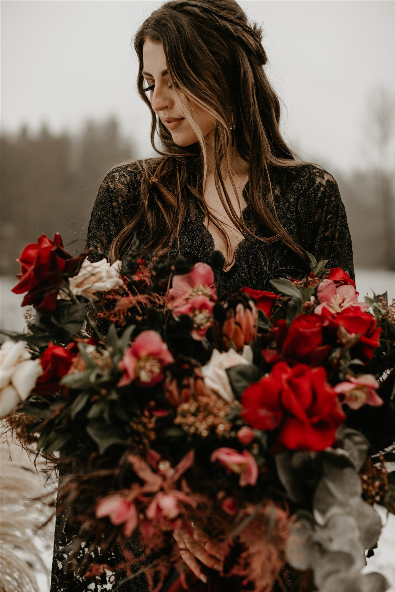 Boho bride with long flowing wedding hair in black wedding dress with large red wedding bouquet