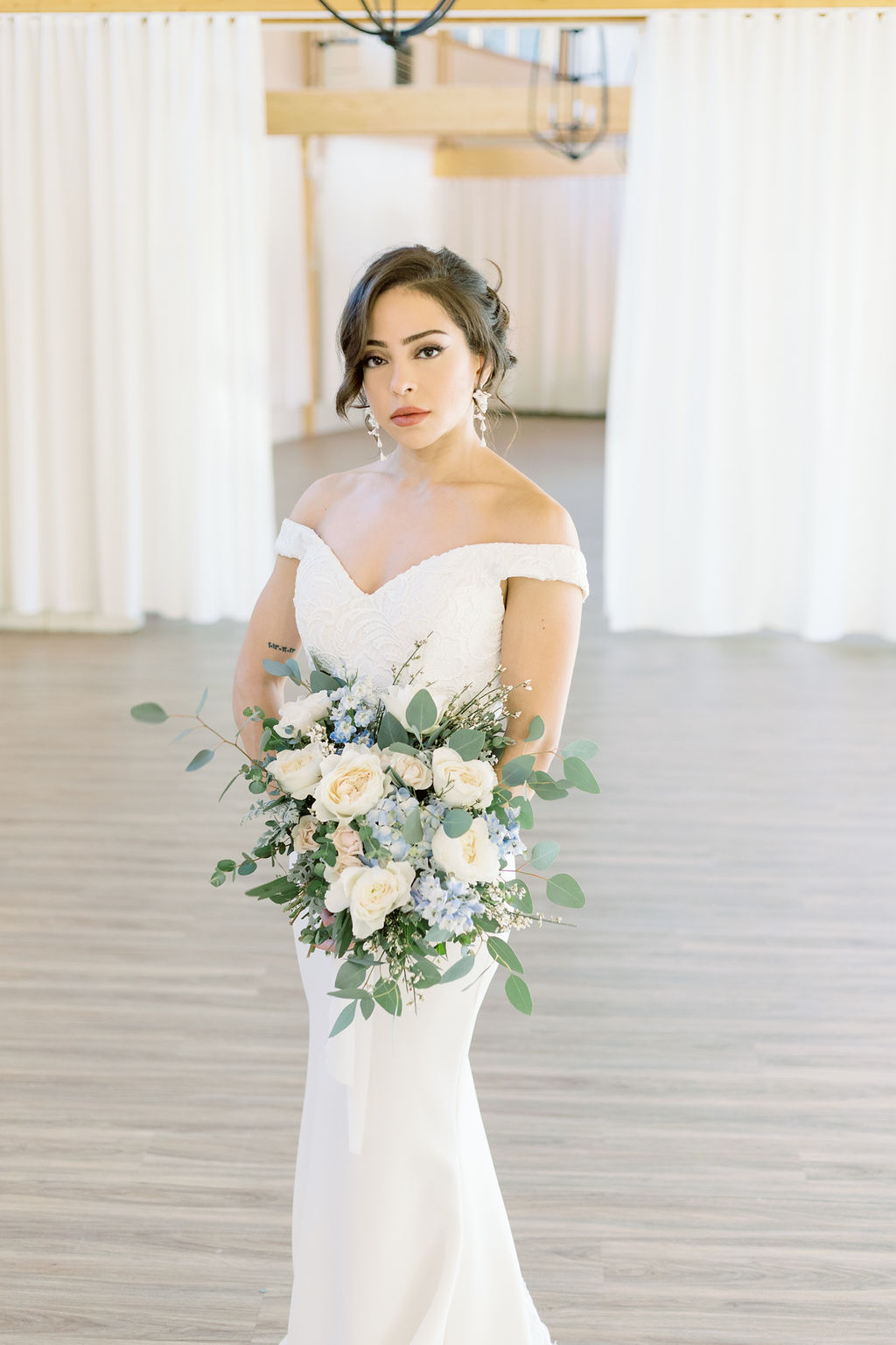 Bride wearing wedding dress with sweetheart neckline holding white and light blue bouquet