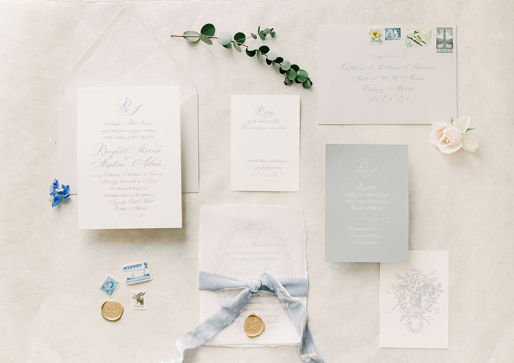 Classic white, ivory and light blue wedding stationery against a linen backdrop