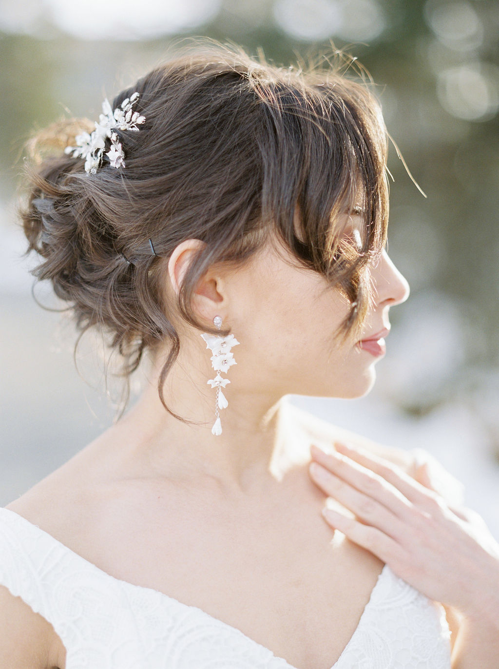 Classic bride with dark brown hair swpet back from her face, one curl in front of her face with a sparkling hair piece and drop earrings