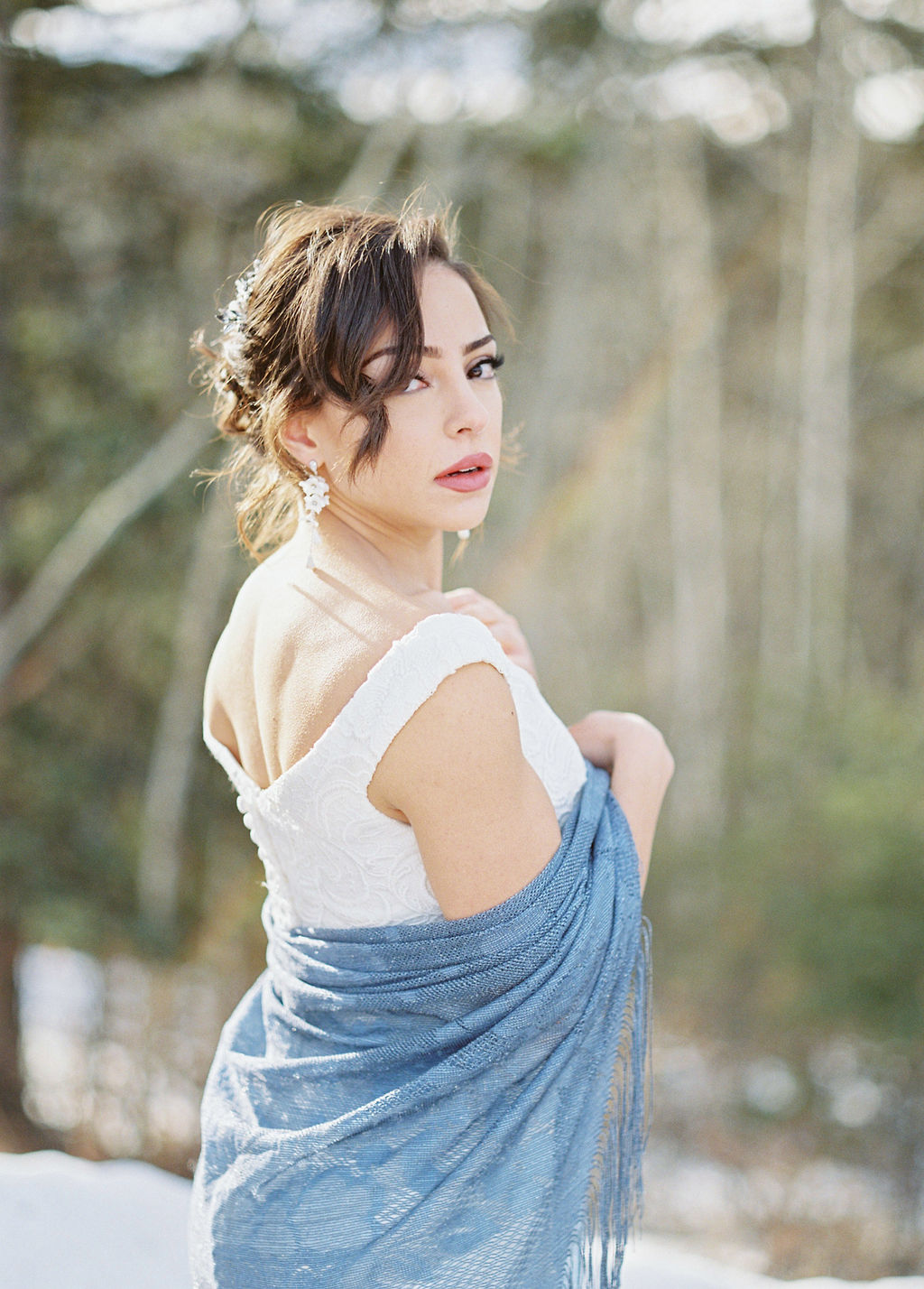 Classic bride with bold lipstick and chandelier earrings looking over her shoulder in in an off the shoulder gown with a sweetheart neckline