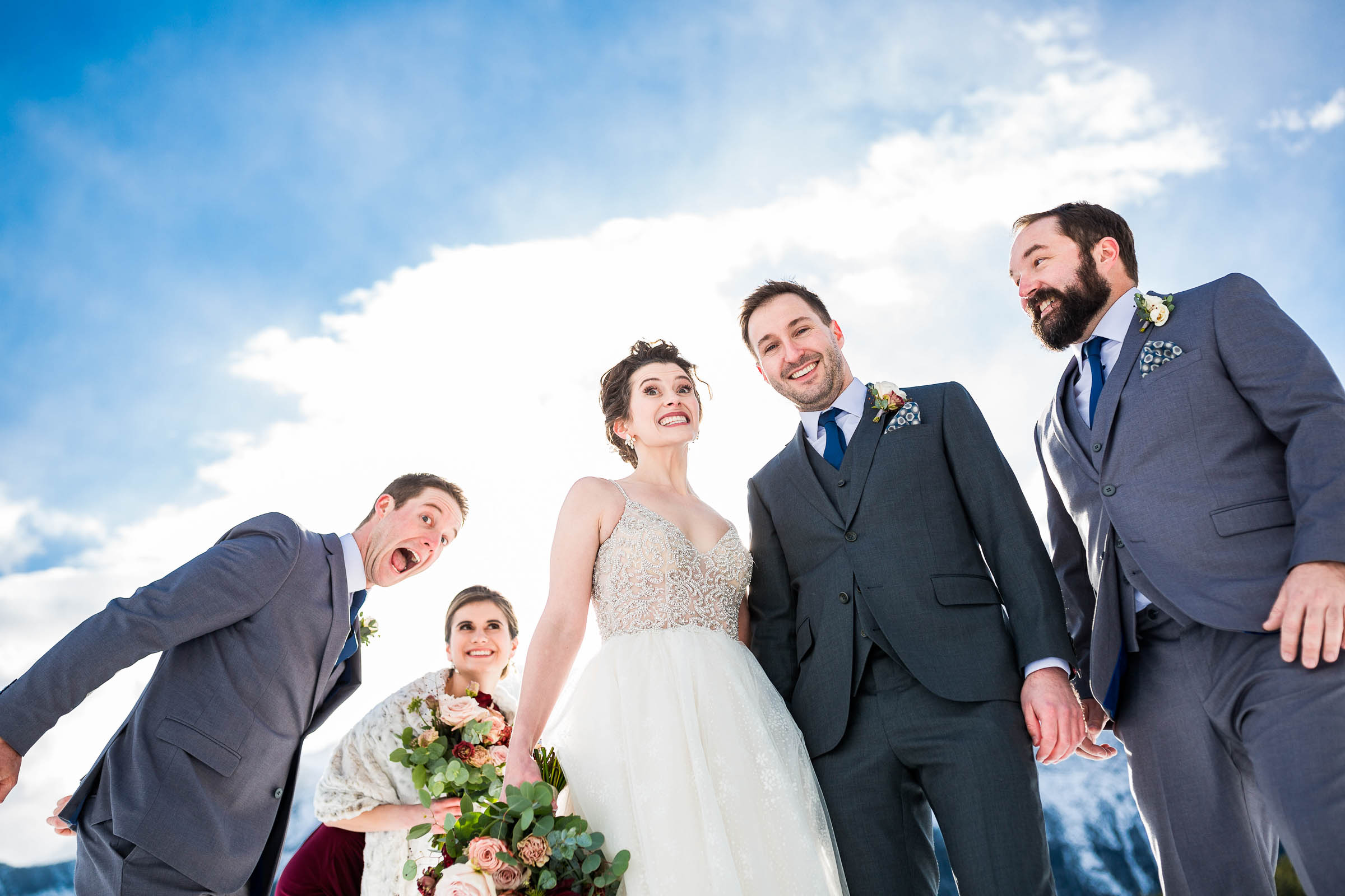 Smiling wedding party against blue sky