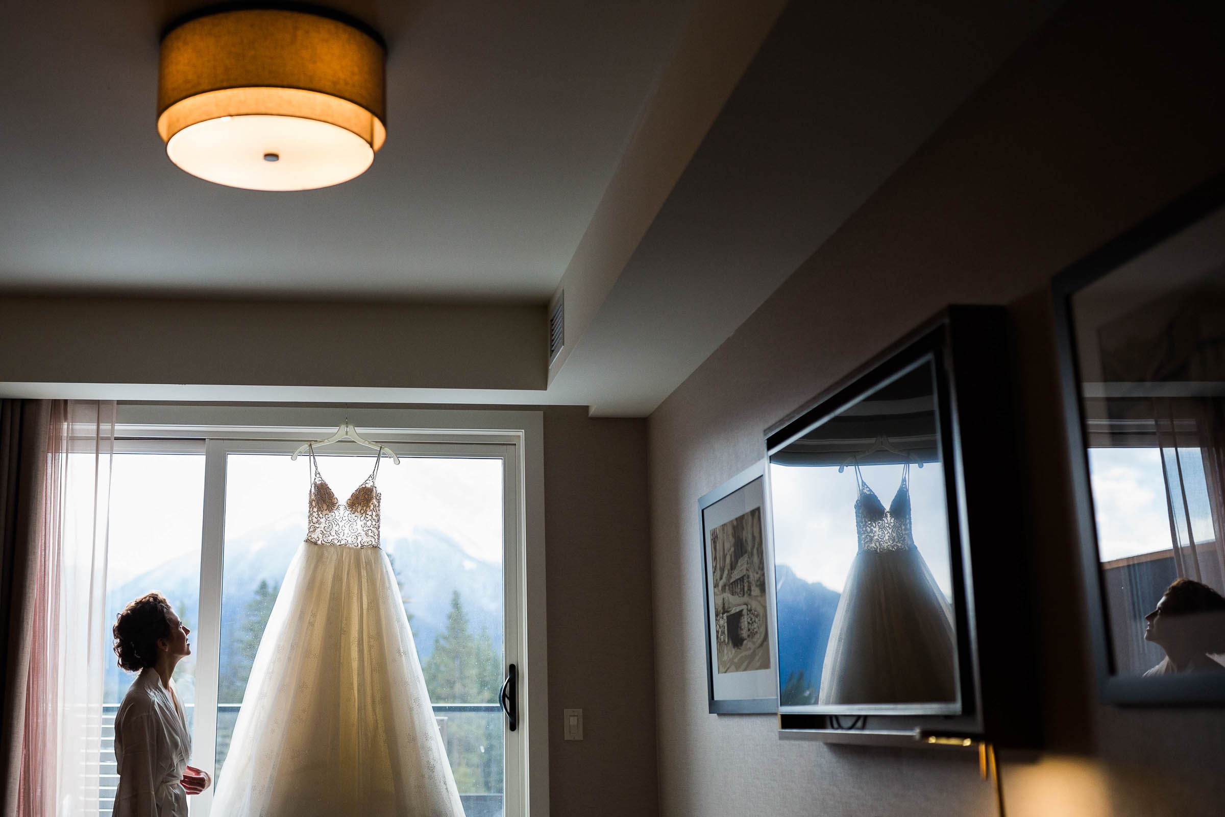 Bride admiring her wedding dress in the light of the window
