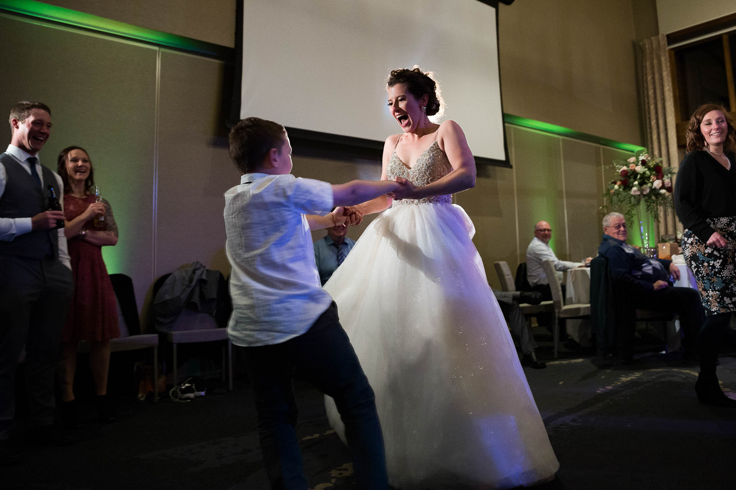 Bride smiling and dancing with child at wedding