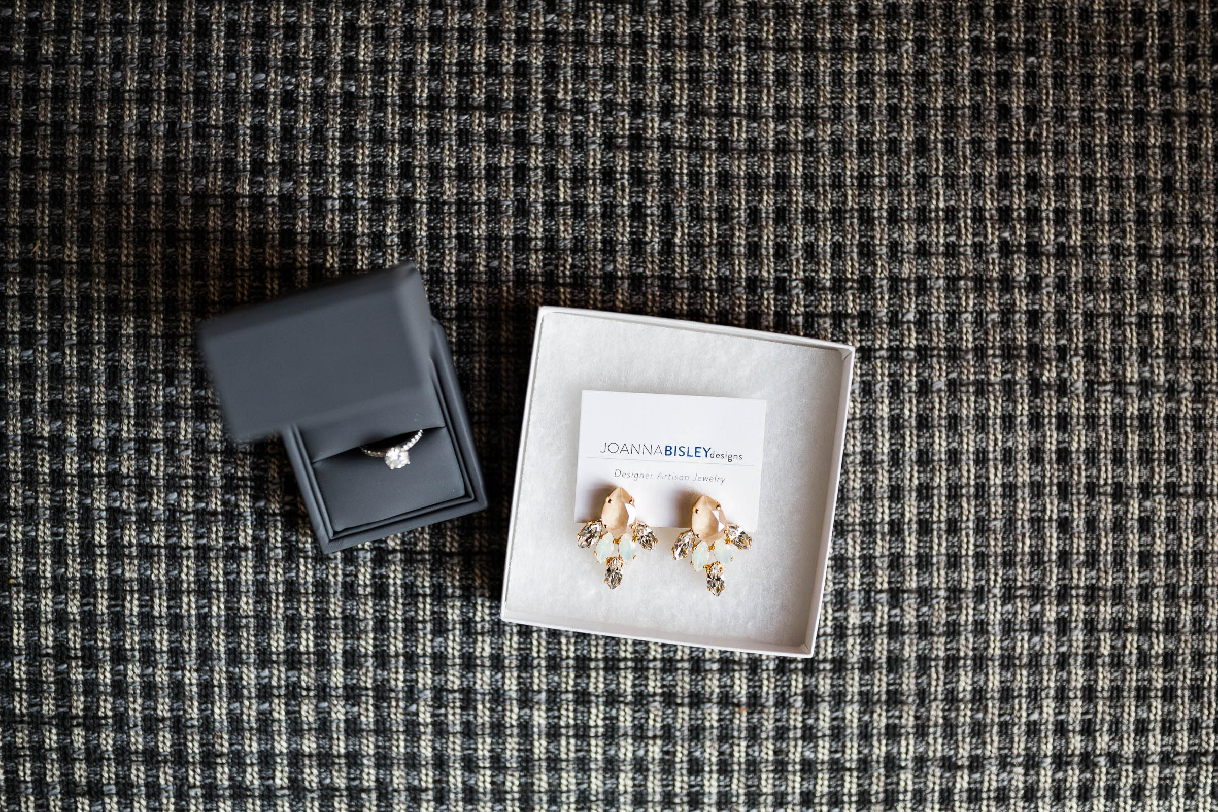 Wedding ring and wedding earrings in boxes against checked backdrop