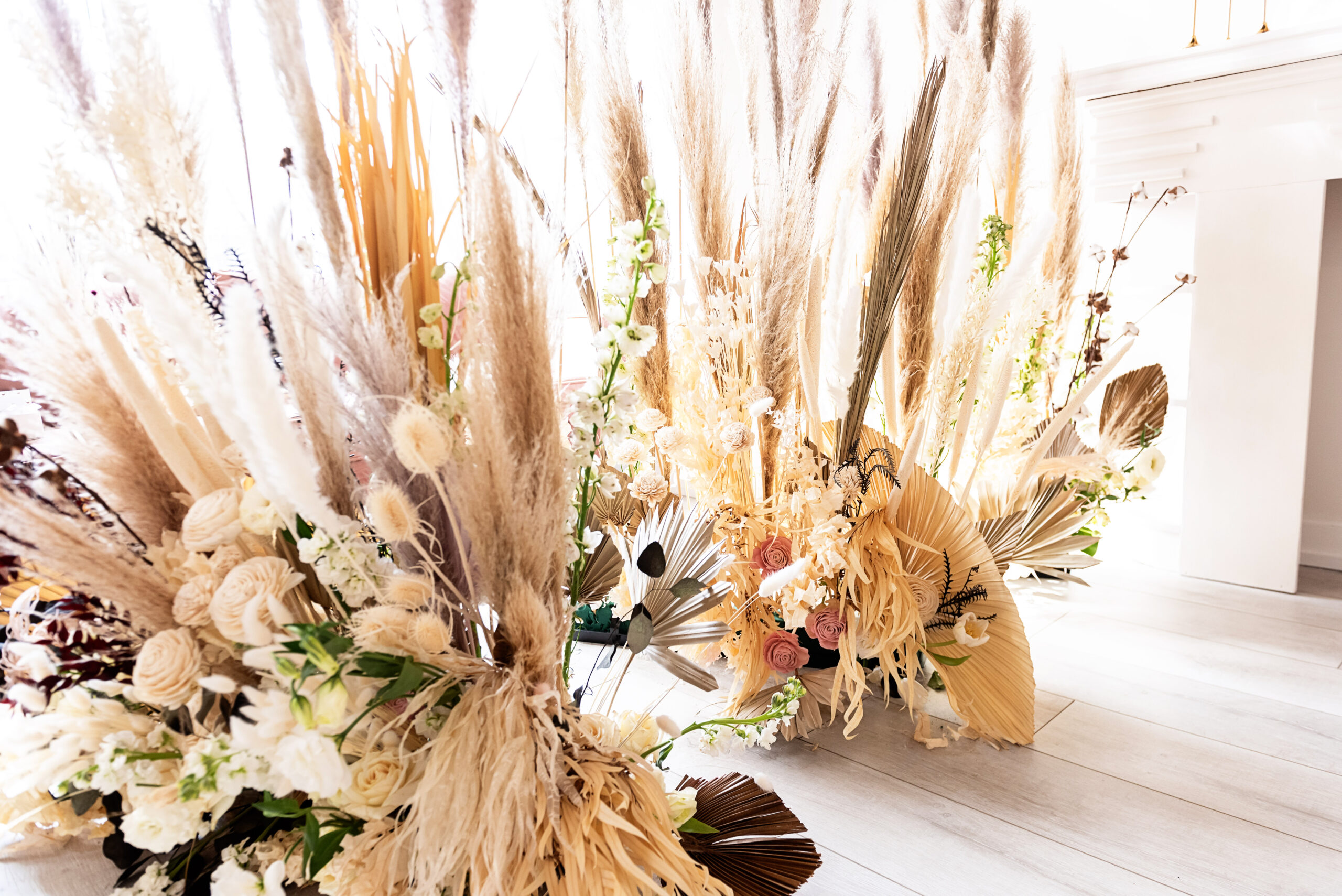 Natural grasses and boho wedding ceremony decor in all white venue