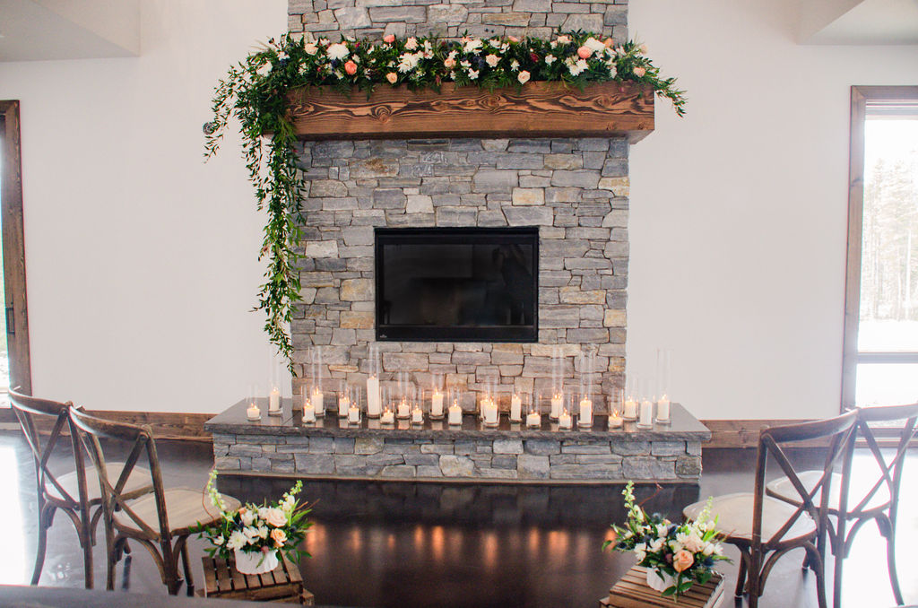 Elegant stone fireplace with mantle covered in garland of wedding flowers