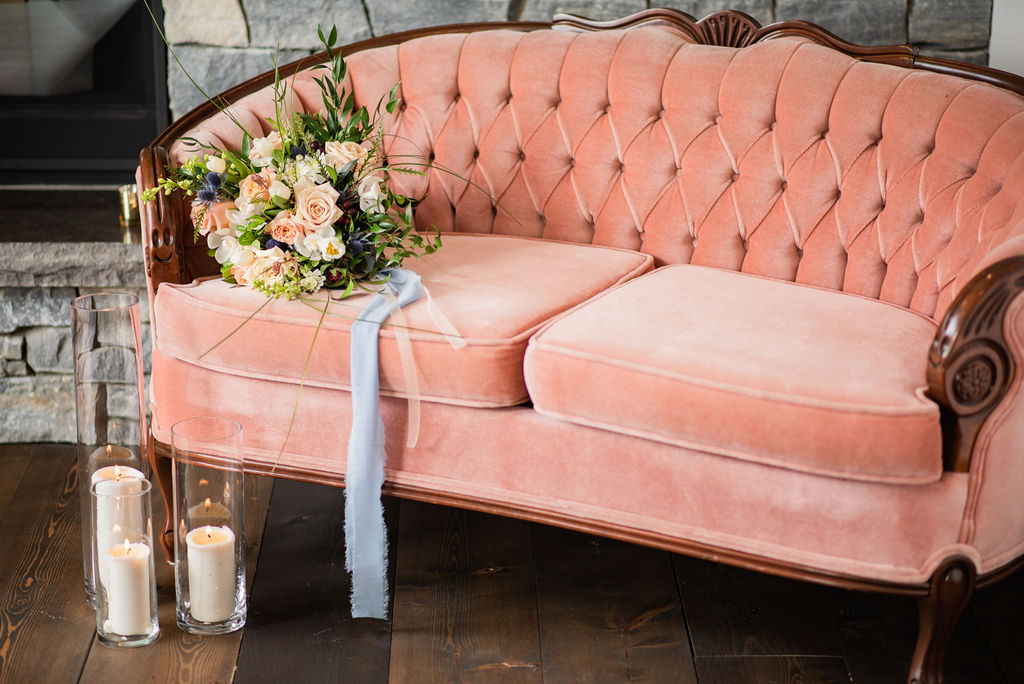 Pink vintage couch with peach and white wedding bouquet with blue ribbon