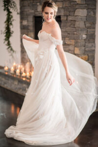 Bride in off the shoulder wedding gown, twirling her skirt