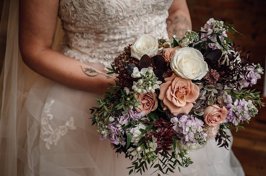 Bride in a ballgown wedding dress holding blush and burgundy wedding bouquet