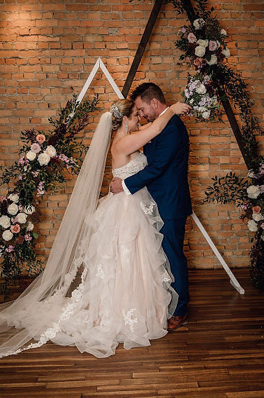 Bride and groom kissing in front of geometric wedding ceremony decor