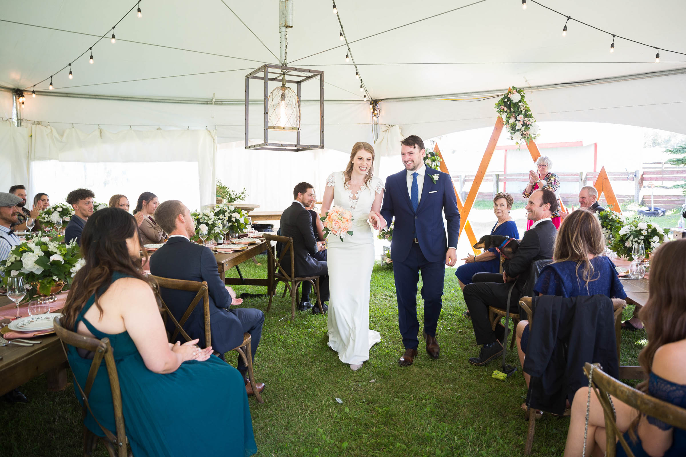 Couple exiting tenting wedding with huge smiles