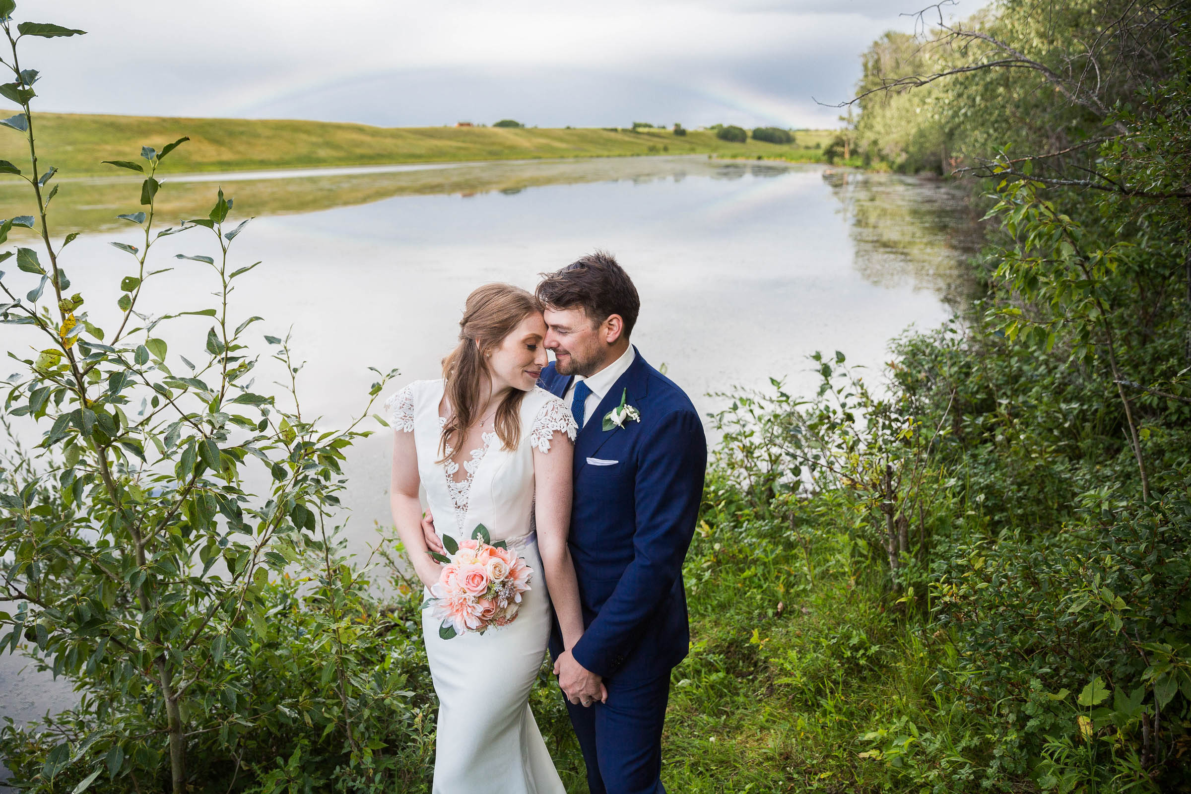Bride and groom embracing infront of small pond