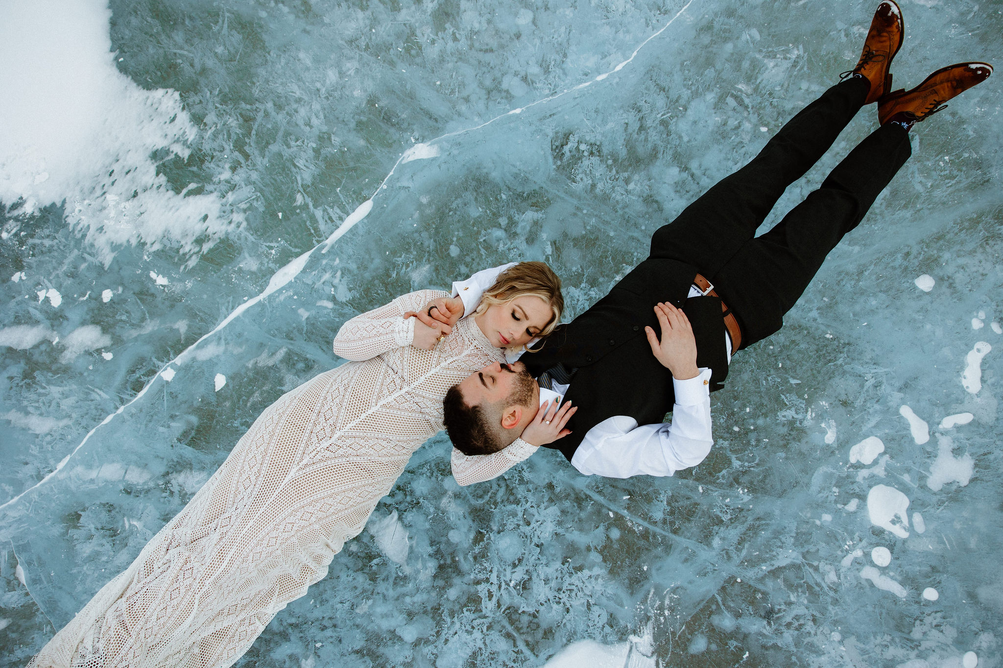 Couple in wedding formal laying down on frozen lake
